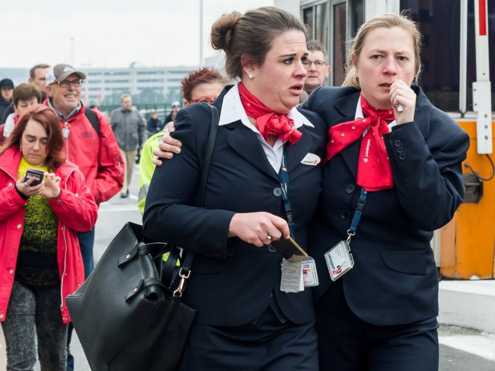 PHOTO: People react as they walk away from Brussels airport after explosions rocked the facility in Brussels, Belgium Tuesday March 22, 2016.